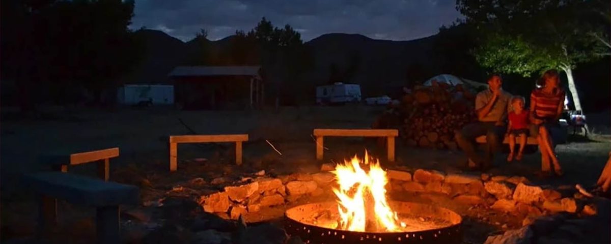 Families gathered around a campfire at Stagecoach Trails Campground during an evening outdoor gathering