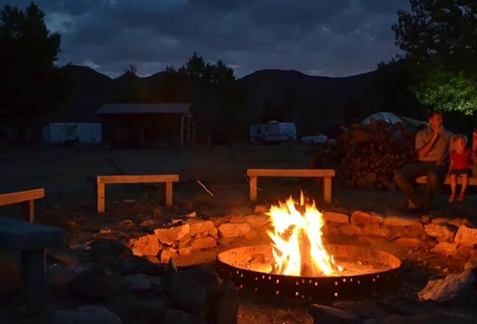 Families gathered around a campfire at Stagecoach Trails Campground during an evening outdoor gathering
