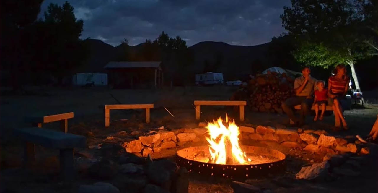 Families gathered around a campfire at Stagecoach Trails Campground during an evening outdoor gathering